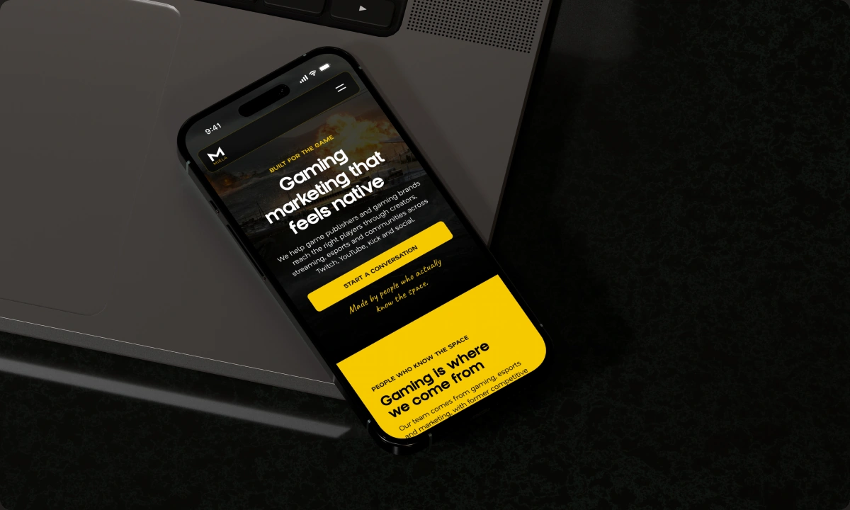 Miela gaming expertise page on a phone beside a laptop