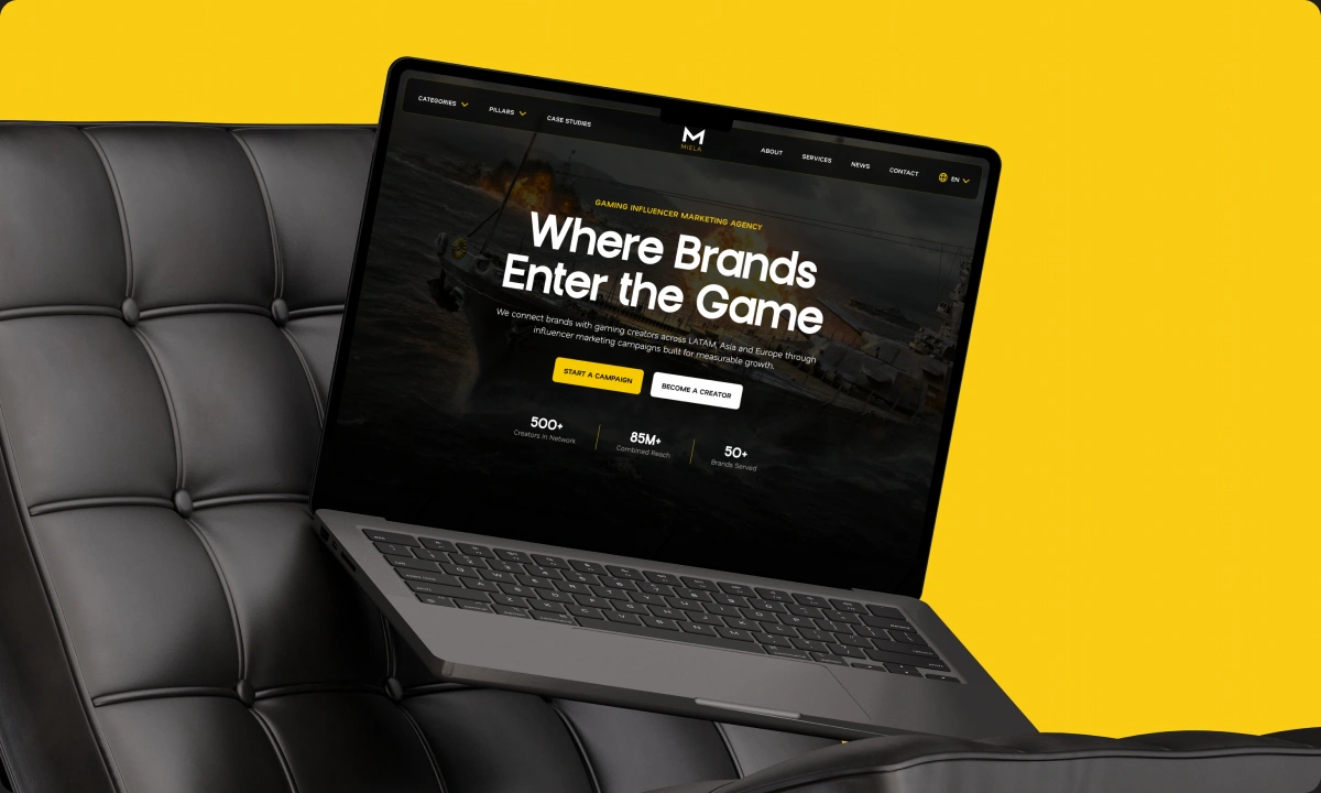 Miela website on a laptop on a leather chair against a yellow background